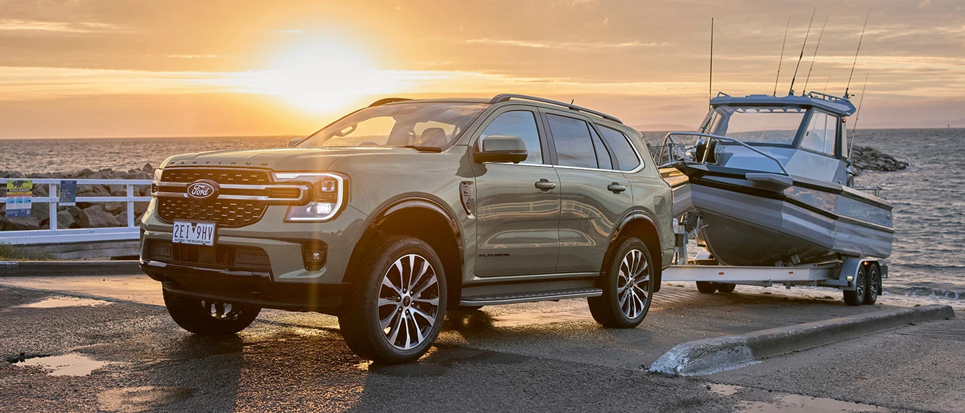SUV towing boat at sunset