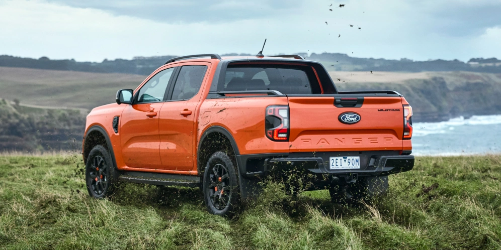 Orange Ford Ranger Wildtrak kicking up dirt on coastal field