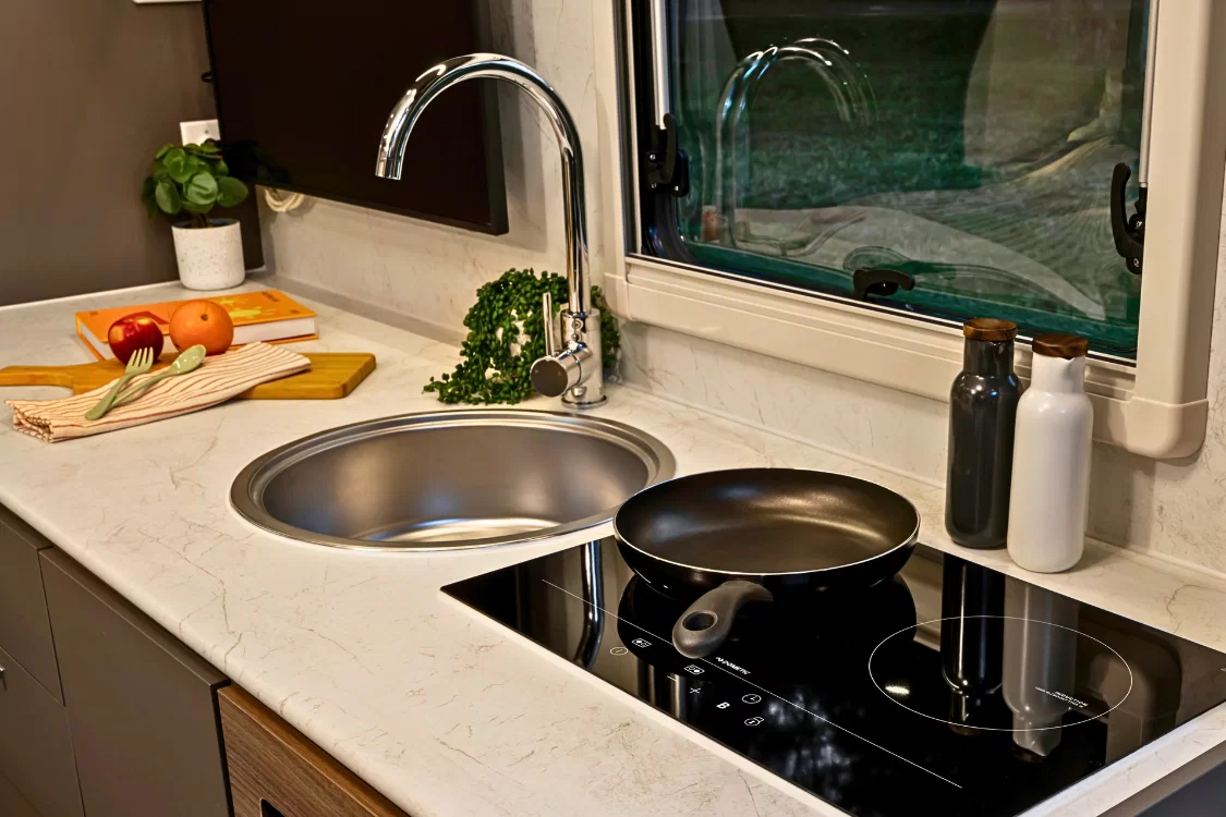 LDV Deliver 9 Motorhome fully equipped kitchen with Dometic twin induction cooktop, marble-look benchtop, integrated microwave and 133L Thetford refrigerator