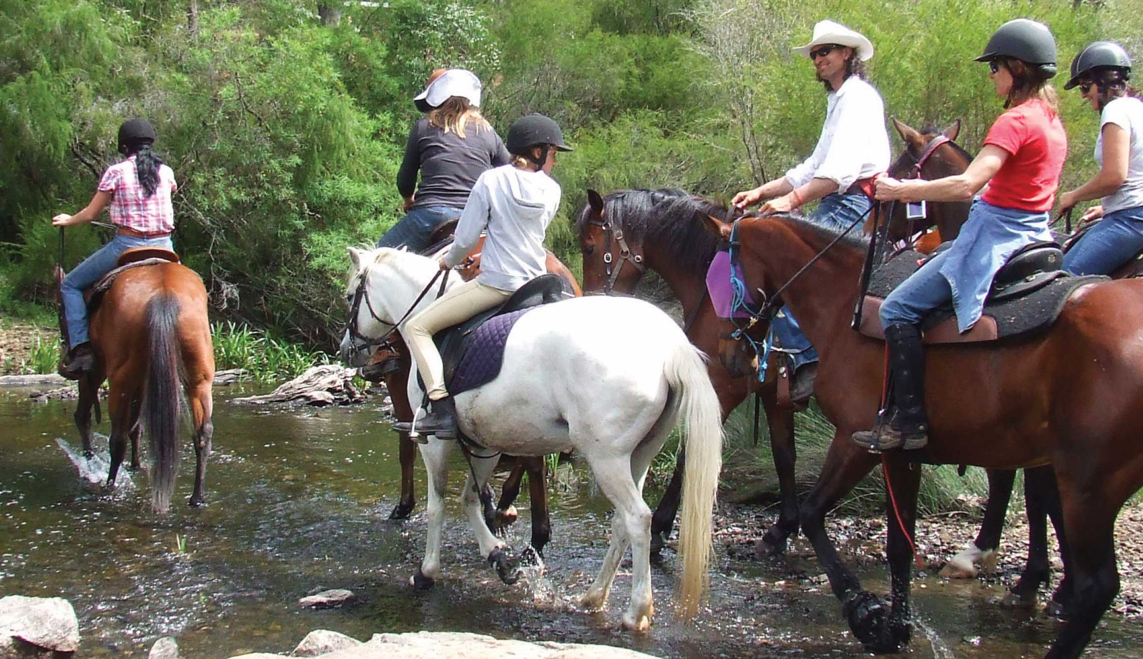 Group of horseriders cross a shallow water crossing 