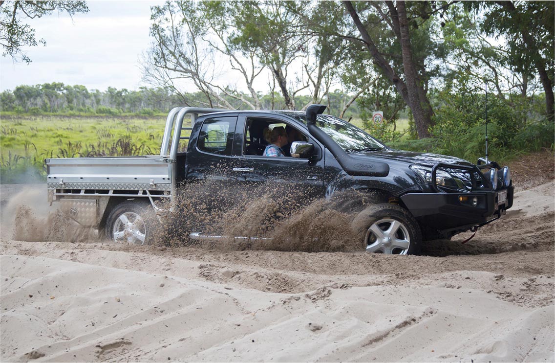 Side angle of D-MAX driving across sand track