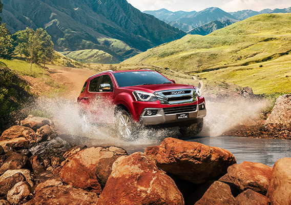 Isuzu MU-X through water crossing with mountainous background