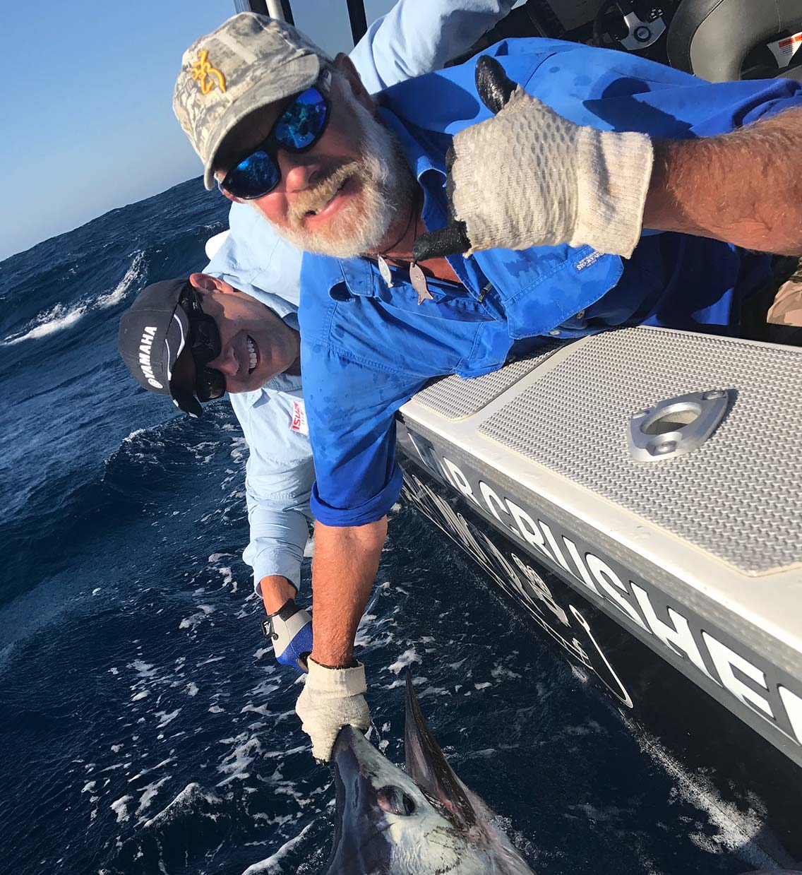  The crew hanging off the boat to grab a marlin