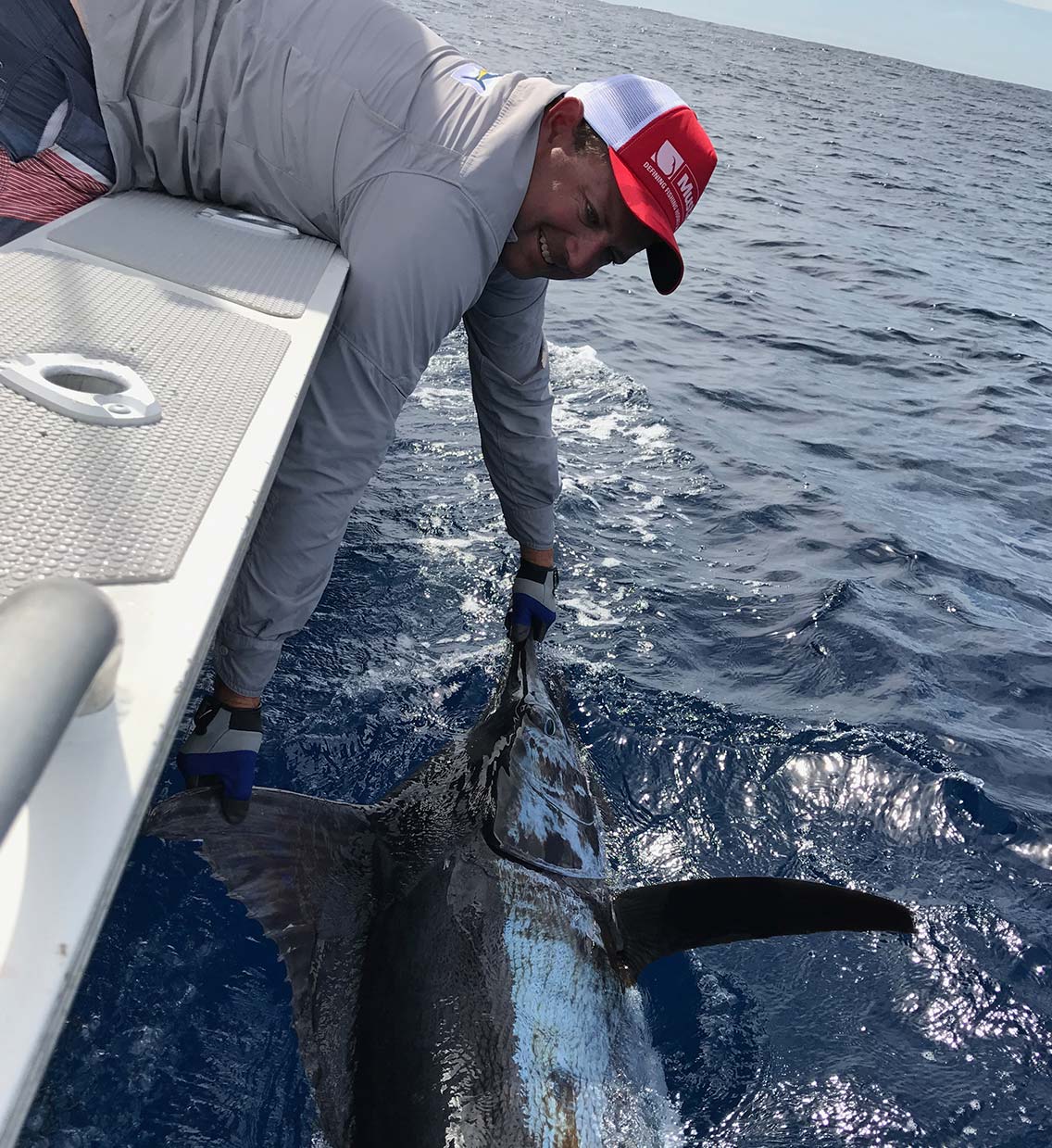 Andrew hanging off the boat to grab a marlin
