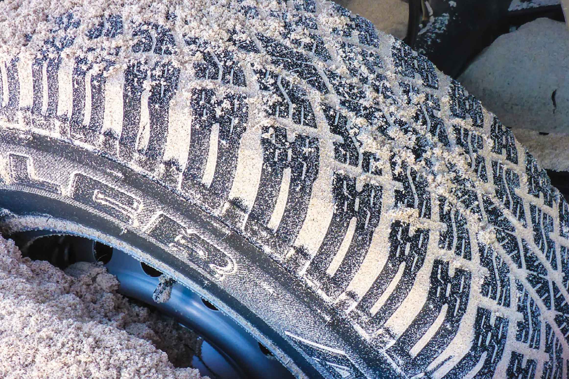 Close-up of sandy tyre sunk into sand