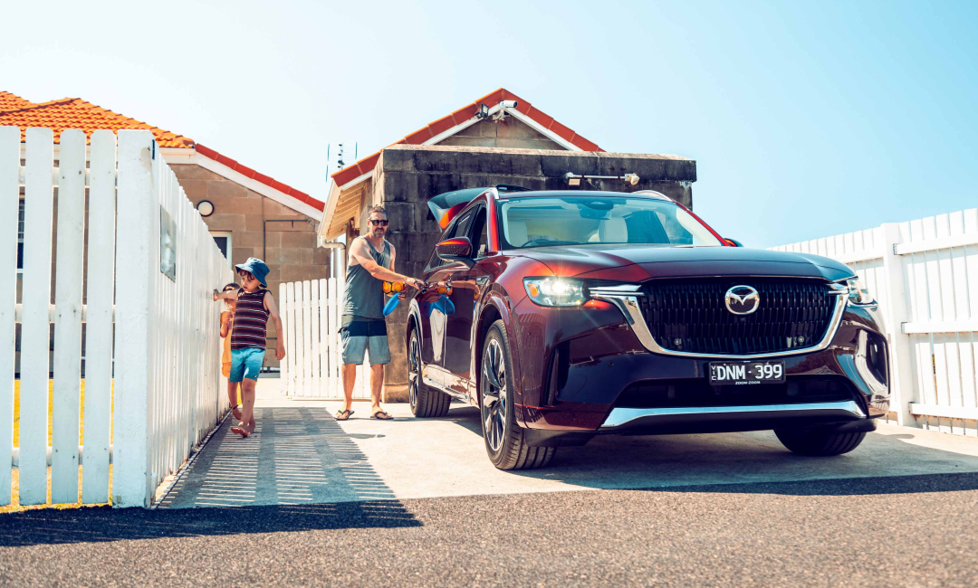 Mazda CX-90 parked at the Norah Head keeper's cottage gate with a father and two children