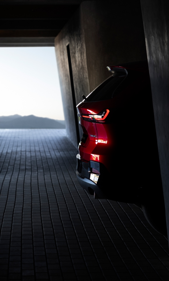 2026 Mazda CX-5 rear view in Soul Red Crystal parked on a scenic overlook with coastal backdrop—sleek SUV design highlighting new taillights, bold rear styling, and panoramic landscape.