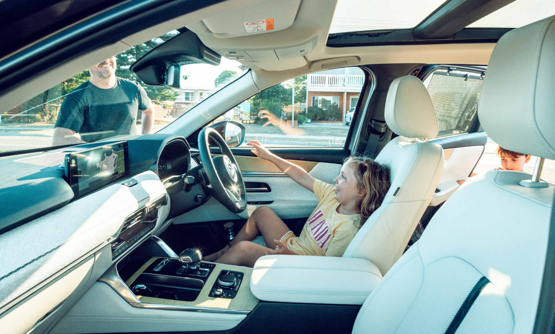 Young girl playing in the driver's seat of the Mazda CX-90 with white leather upholstery