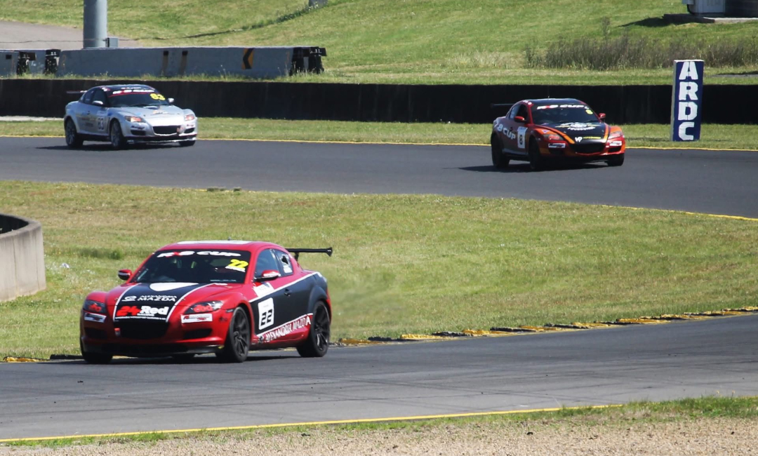 Stiaan Kriel's car leading a group of competitors through a corner at the 2025 Mazda RX‑8 Cup.