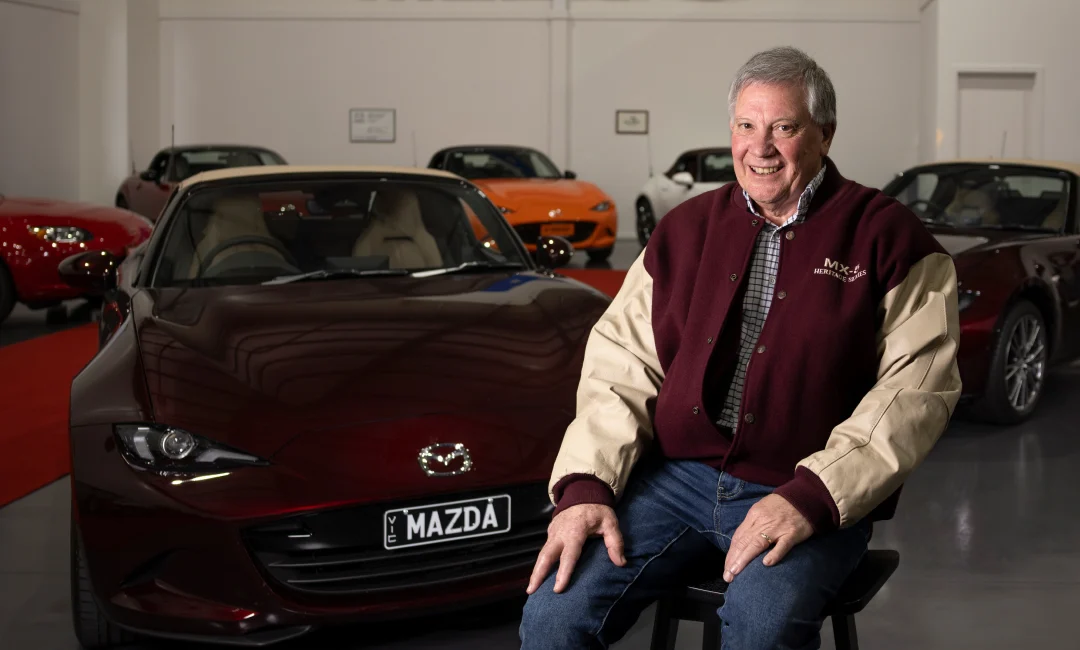 Mazda MX-5 35th Anniversary Edition in deep burgundy showcased in a premium indoor collection, with multiple generations of MX-5 roadsters displayed in the background, celebrating Australia’s greatest MX-5 collection.
