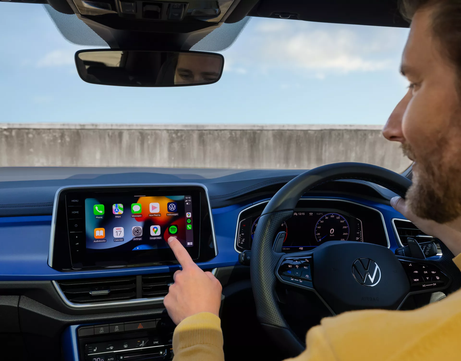Man in the driving seat touching the infotainment system inside the Volkswagen T-Roc R.